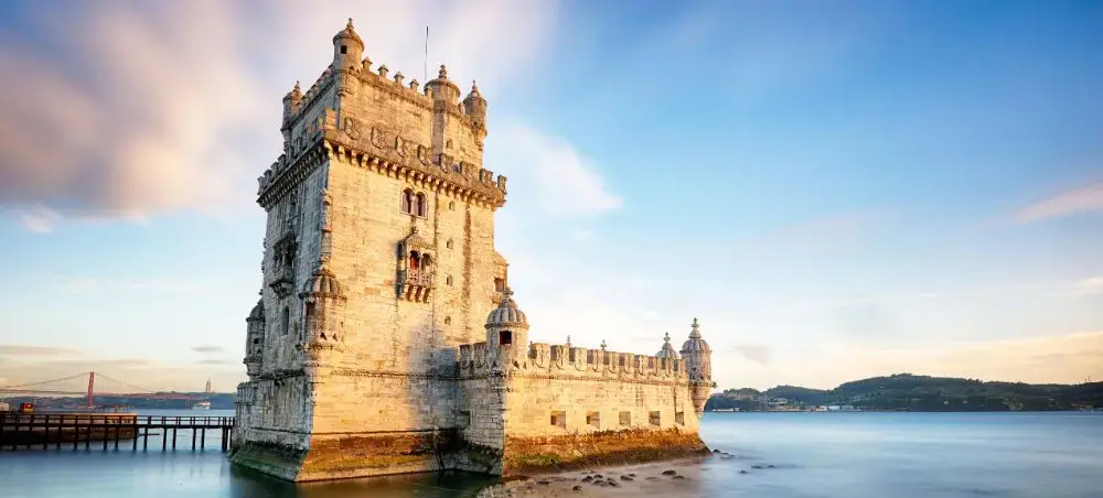 Historic Belém Tower fortress standing in Lisbon's Tagus River at golden hour, iconic Portuguese landmark