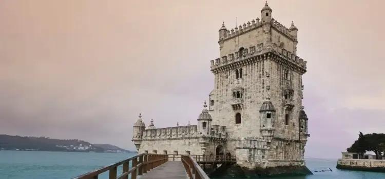 Historic Belém Tower fortress standing majestically on Lisbon's Tagus River waterfront at sunset