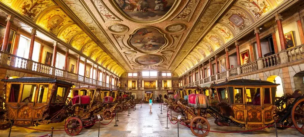 Ornate royal carriage collection displayed in gilded museum hall showcasing Lisbon's imperial heritage