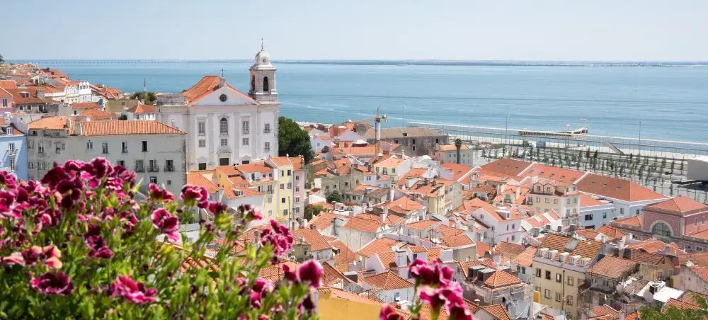 Panoramic view of Lisbon's colorful terracotta rooftops cascading toward the Tagus River waterfront