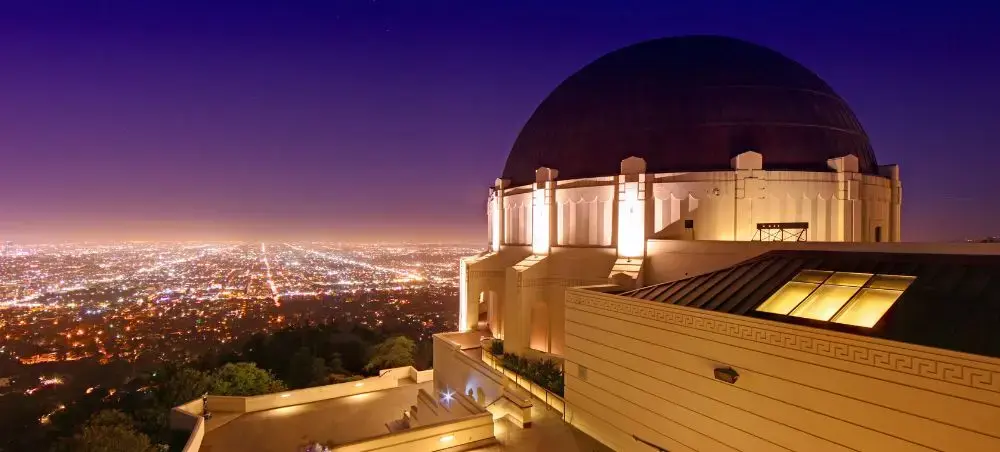 Griffith Observatory illuminated at twilight overlooking sprawling Los Angeles cityscape with twinkling lights