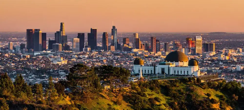 Los Angeles skyline at golden hour with Griffith Observatory overlooking downtown skyscrapers and urban sprawl