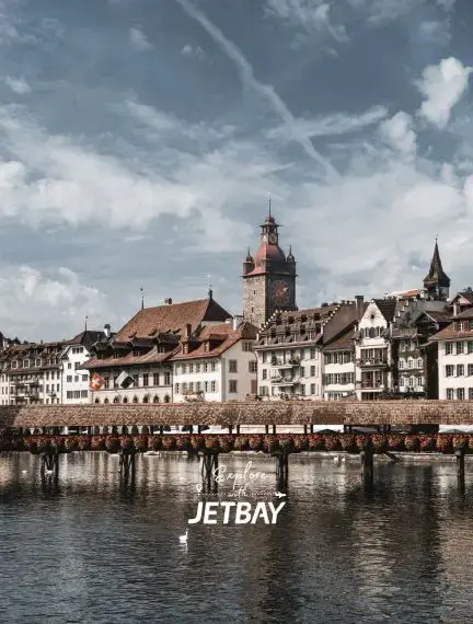 Historic Chapel Bridge spans Lake Lucerne with medieval clock tower and traditional Swiss buildings