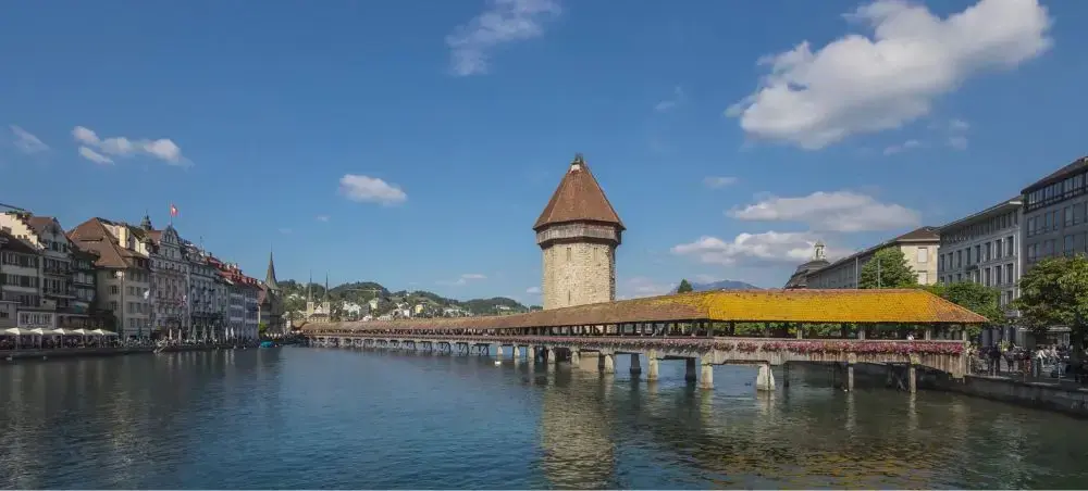 Historic Chapel Bridge with medieval water tower spanning Reuss River in Lucerne's charming old town center