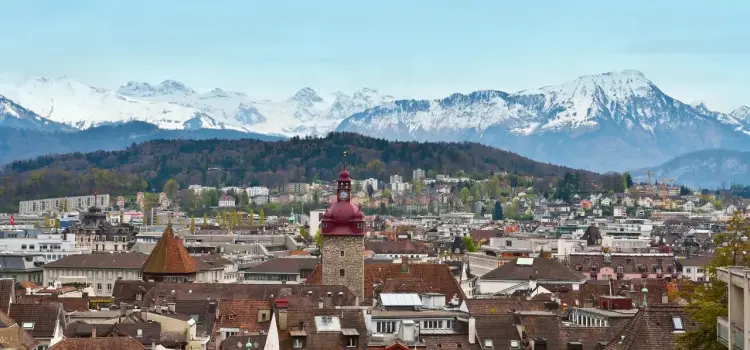 Lucerne cityscape with historic red tower and snow-capped Swiss Alps creating stunning mountain backdrop