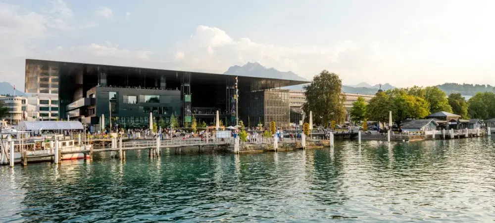 Modern Lucerne Culture and Congress Centre overlooking pristine lake waters with mountain backdrop in Switzerland