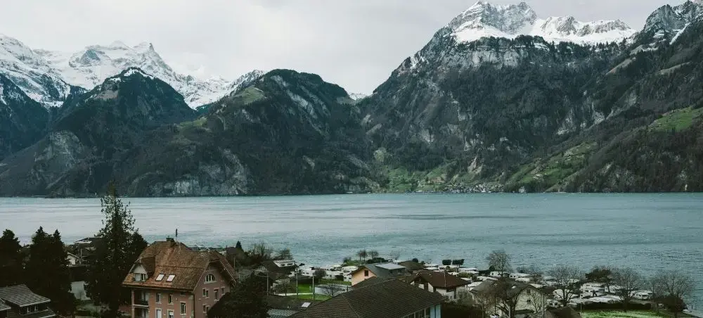 Scenic lakeside village nestled beneath snow-capped Swiss Alps mountains near Lucerne, Switzerland