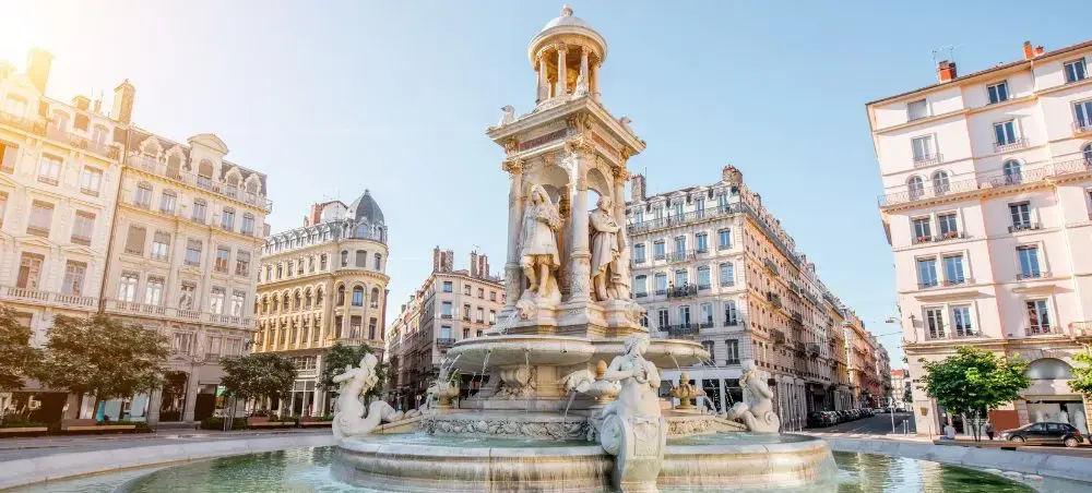 Historic fountain with ornate sculptures surrounded by elegant Haussmann-style buildings in Lyon's city center
