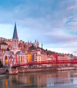Lyon's historic riverside district with Gothic cathedral and colorful buildings reflecting in Saône River at sunset