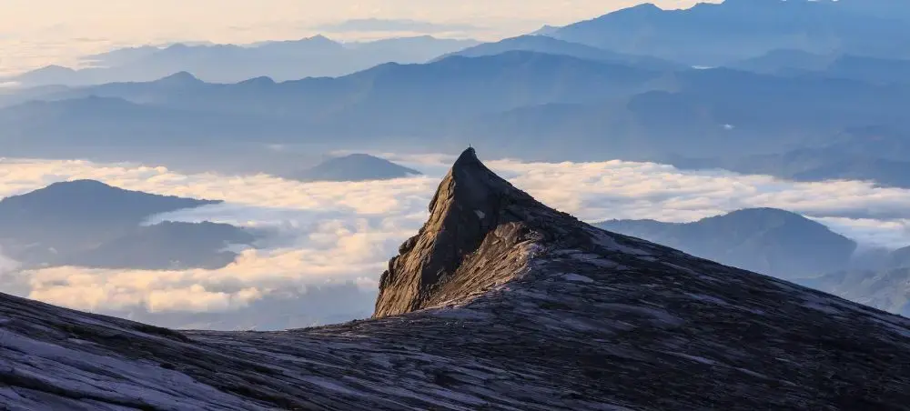 Dramatic mountain peak rising above clouds in Malaysia's highlands during golden hour sunrise