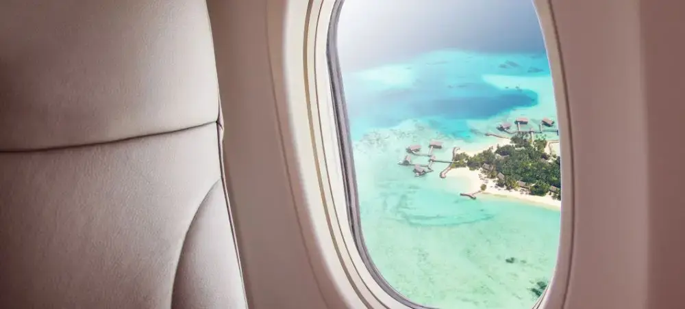 Luxury private jet window view of pristine Maldives resort with overwater villas and turquoise lagoon