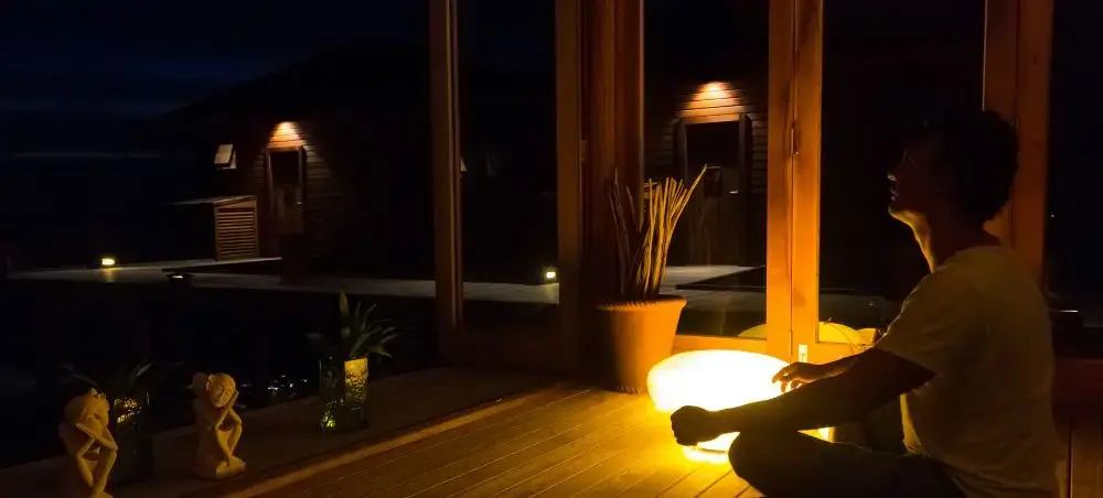 Traveler relaxing on illuminated wooden deck of luxury Maldives resort villa during peaceful evening