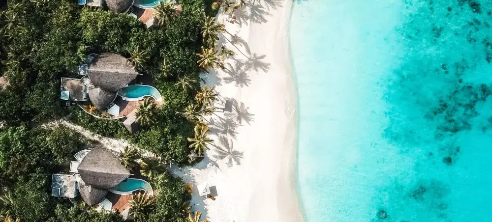 Aerial view of luxury overwater villas with private pools and pristine turquoise lagoon in the Maldives