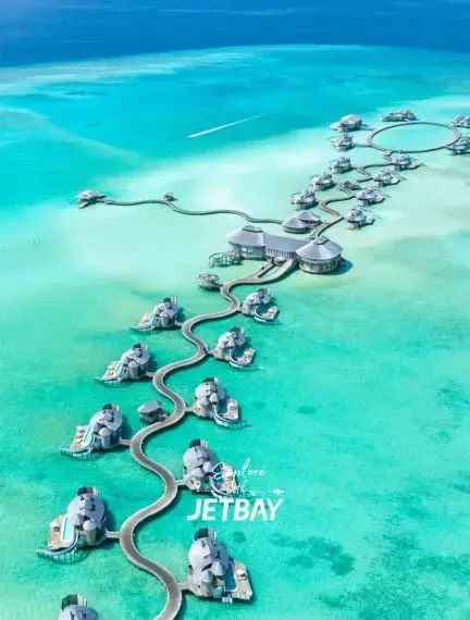 Luxury overwater villas connected by wooden walkways in turquoise Maldivian lagoon near Male