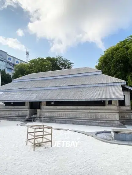 Traditional Maldivian architecture with corrugated metal roof and white sand courtyard in Male