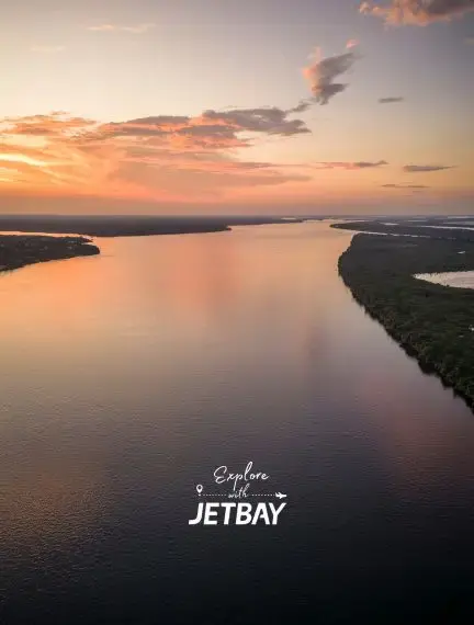 Aerial sunset view over Amazon River near Manaus showing golden reflections and lush rainforest coastline