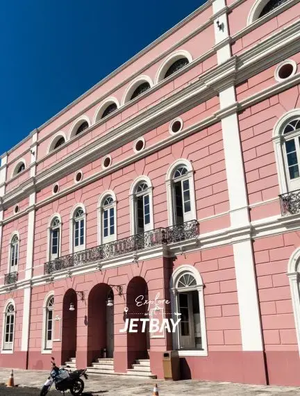 Historic pink colonial opera house facade with ornate balconies under blue sky in Manaus, Brazil