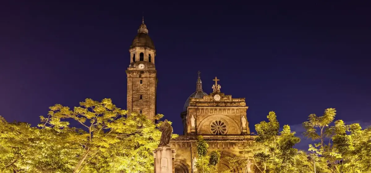 Manila Cathedral's illuminated baroque bell tower and dome against twilight sky showcasing Philippines capital