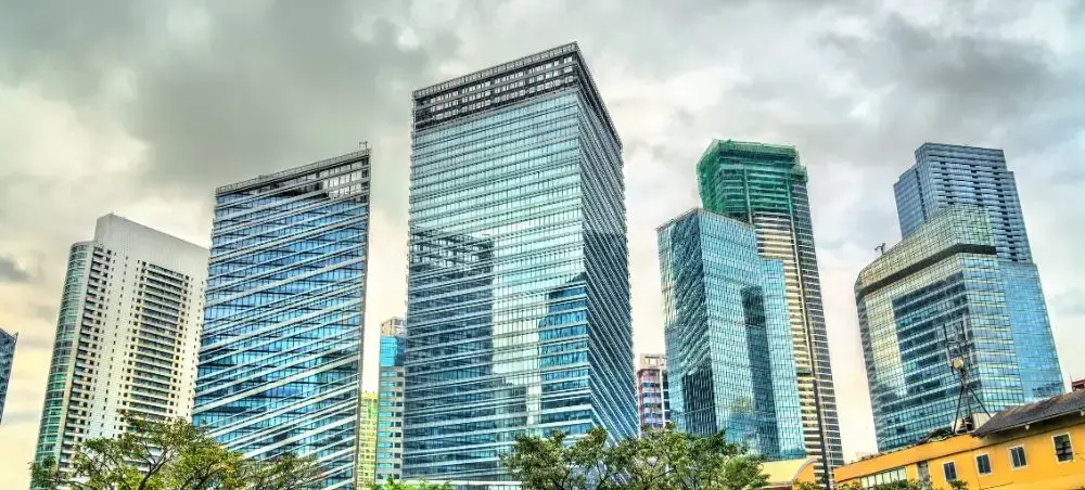 Modern glass skyscrapers dominate Manila's business district skyline under dramatic cloudy skies