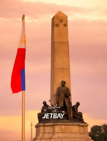 Rizal Monument in Manila at sunset with Philippine flag, showcasing the capital's historic landmarks
