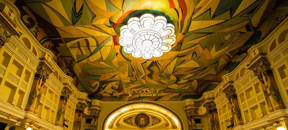Ornate golden ceiling with vibrant floral mural and crystal chandelier in historic Maracaibo theater