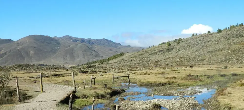 High-altitude Andean landscape near Merida with mountain streams, wooden bridges, and rugged terrain under clear blue skies