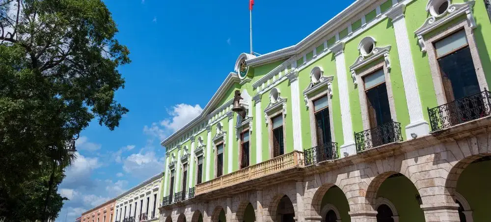 Historic colonial architecture with vibrant green facade and stone arches in downtown Merida, Venezuela