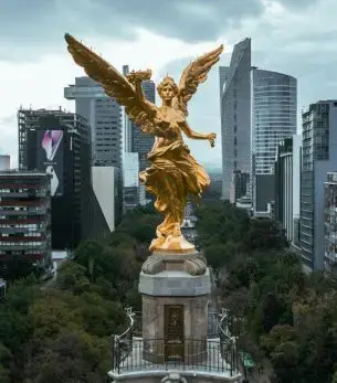 Golden Angel of Independence monument towering over Mexico City's modern skyline and lush parkland