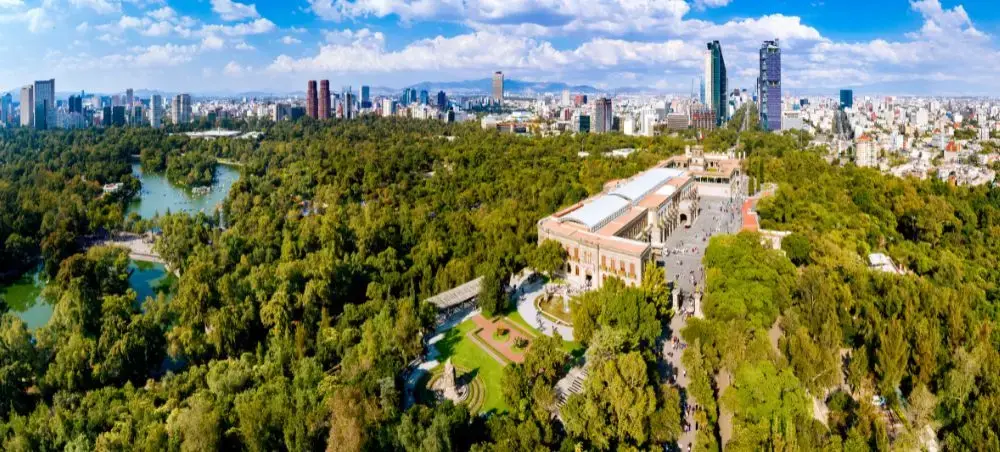 Aerial view of Chapultepec Castle surrounded by lush parkland with Mexico City's modern skyline beyond