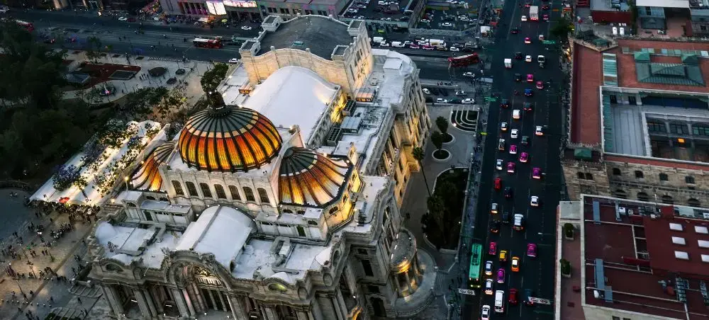 Aerial view of Palacio de Bellas Artes with its distinctive golden domes illuminated at dusk in Mexico City