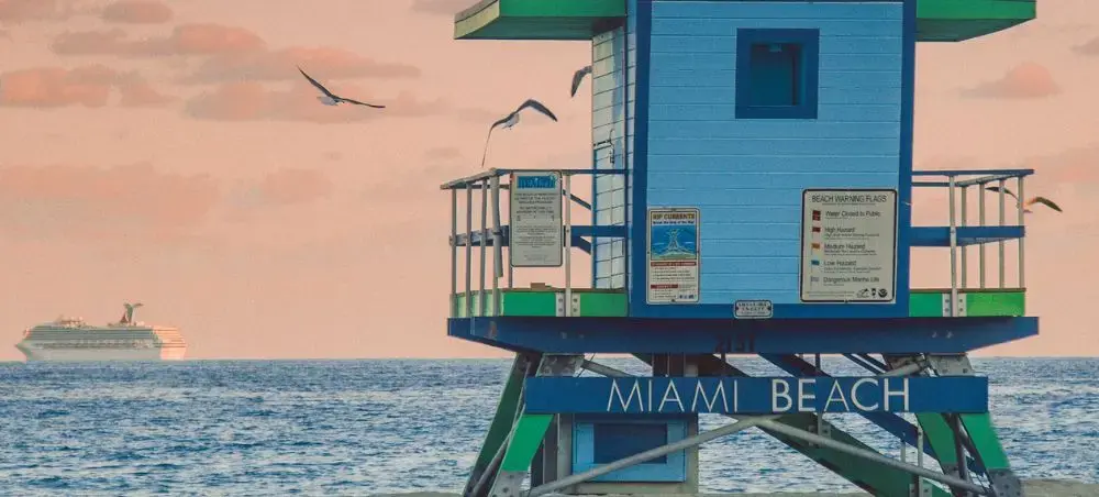 Iconic Miami Beach lifeguard tower overlooking Atlantic Ocean with cruise ship and seagulls at sunset