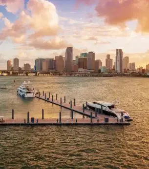 Miami skyline at golden hour with luxury yachts docked at marina, showcasing premium waterfront lifestyle