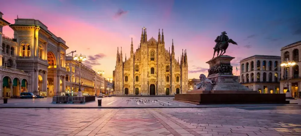 Milan's iconic Duomo cathedral illuminated at sunset in Piazza del Duomo with historic architecture