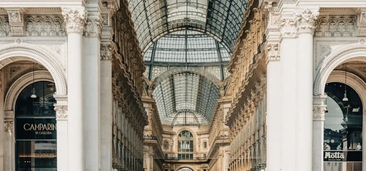 Elegant glass-vaulted arcade with ornate columns and luxury boutiques in Milan's historic center