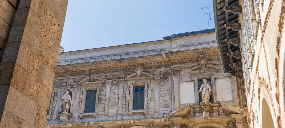 Historic Milanese palazzo facade with ornate baroque sculptures and architectural details in golden sunlight