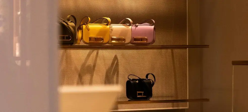 Luxury designer handbags displayed on illuminated shelves in Milan's high-end fashion boutique