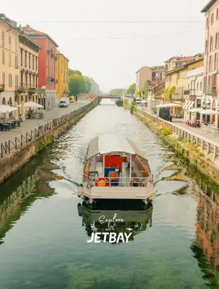 Traditional boat navigating Milan's historic Navigli canal district with colorful waterfront buildings