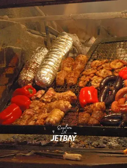 Traditional Uruguayan barbecue grill with chorizo sausages and red peppers cooking over open flames
