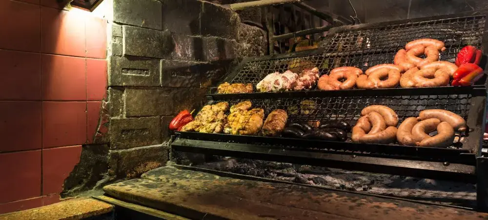 Traditional Uruguayan barbecue grill with sausages and meat cooking over open flames in Montevideo restaurant