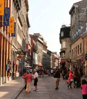 Historic cobblestone street in Old Montreal with tourists exploring charming European-style architecture