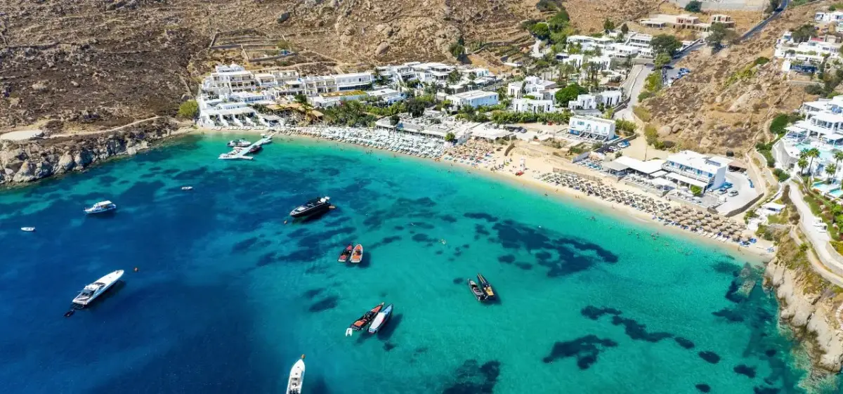 Aerial view of turquoise Mediterranean waters surrounding luxury yachts anchored near Mykonos coastline