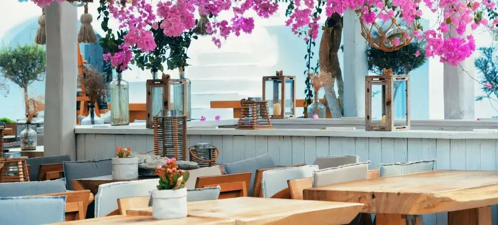 Elegant Mediterranean restaurant terrace in Mykonos with bougainvillea flowers and ocean views