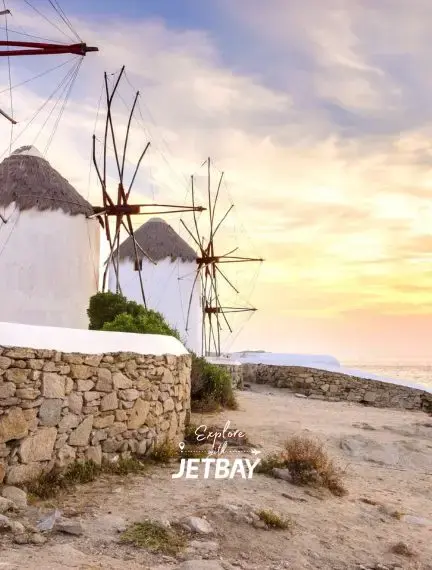 Traditional whitewashed windmills overlooking the Aegean Sea at sunset in Mykonos, Greece
