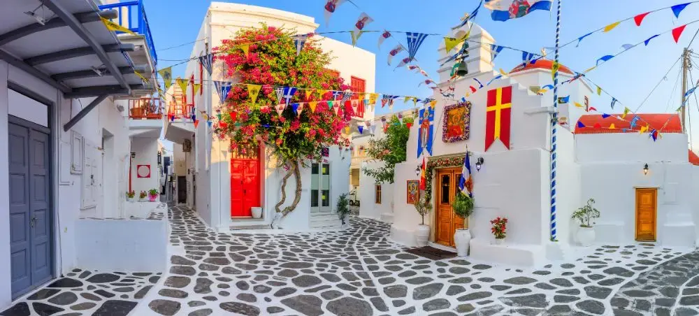 Traditional whitewashed buildings with colorful doors and festive bunting in charming Mykonos village square