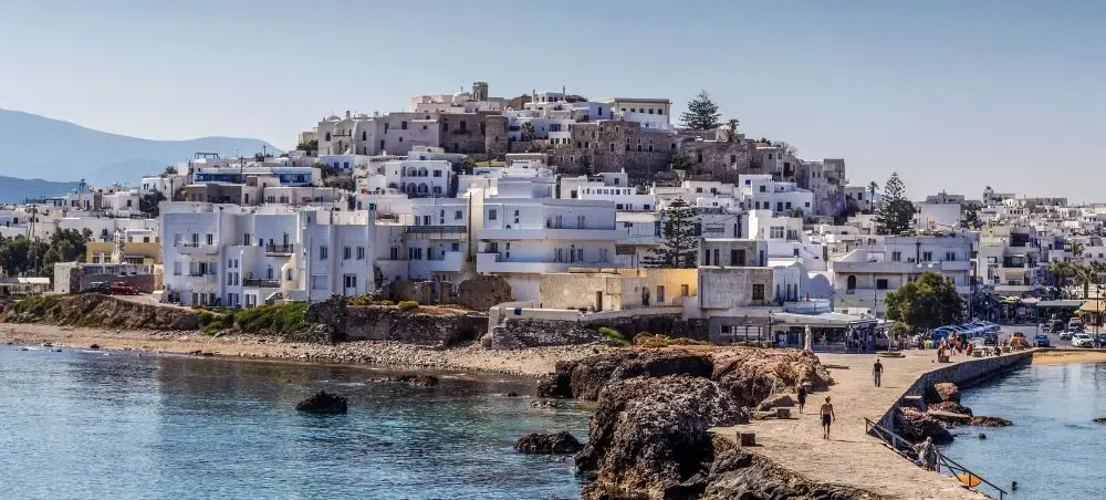 Whitewashed buildings cascade down hillside to turquoise waters in picturesque Mykonos town, Greece