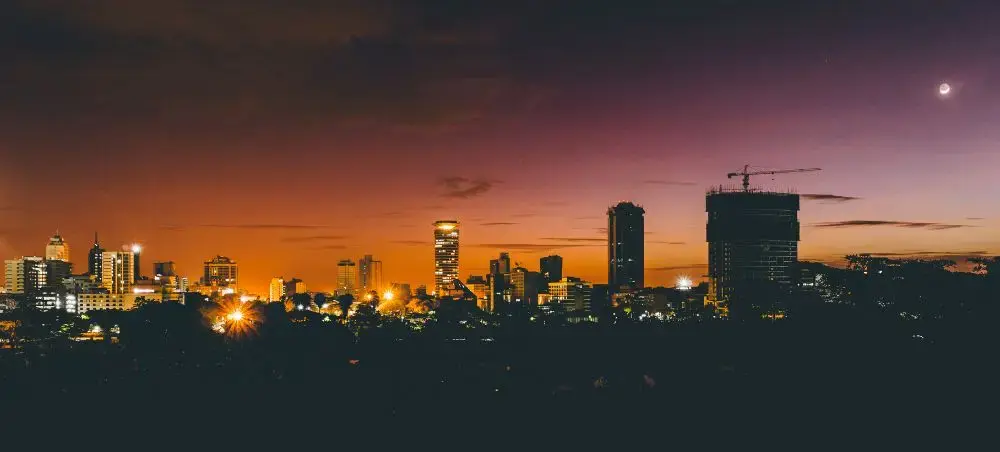 Nairobi skyline at dusk with illuminated buildings and purple-orange sunset sky showcasing Kenya's capital city