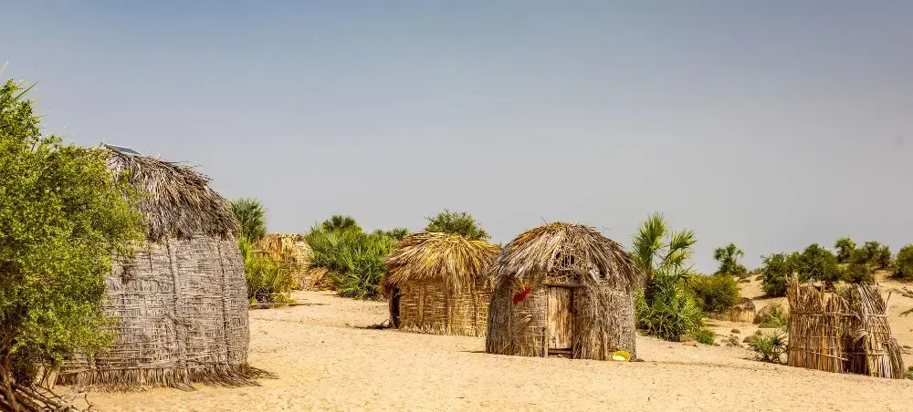 Traditional thatched huts in arid Kenyan landscape showcasing authentic rural architecture near Nairobi