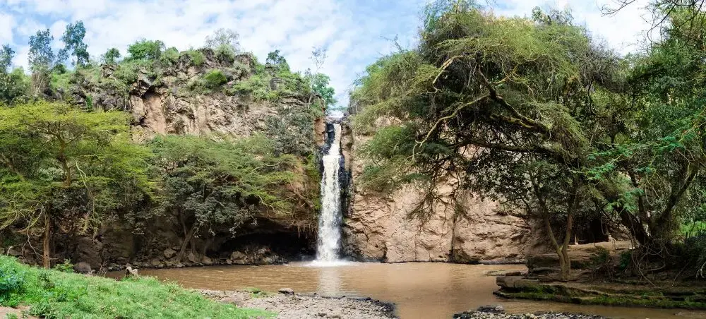 Scenic waterfall cascading into natural pool surrounded by lush vegetation in Nakuru's pristine wilderness