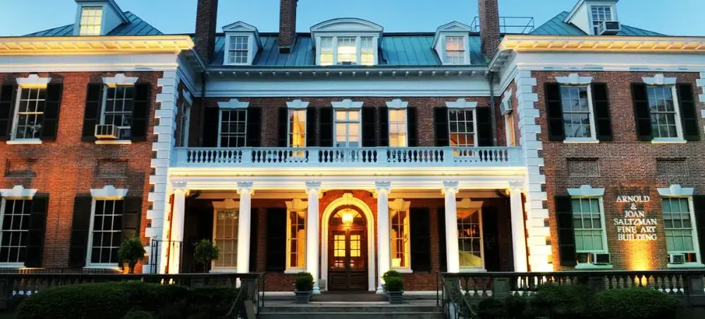 Historic colonial mansion with illuminated white columns and red brick facade in Nassau's downtown district