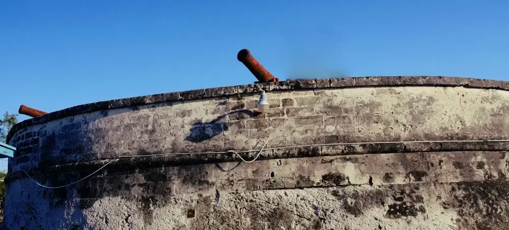 Historic stone fortification walls with cannons overlooking Nassau harbor under clear Caribbean skies